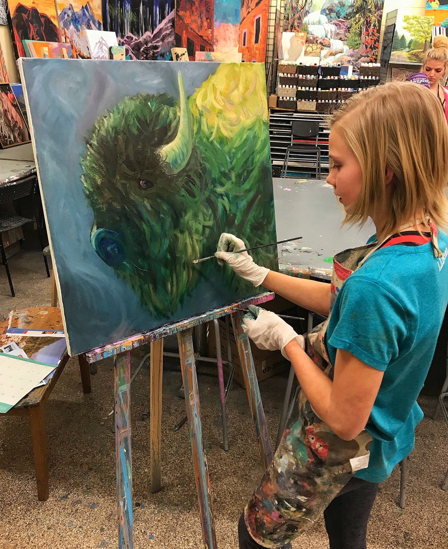 Young girl painting a large bison in oil