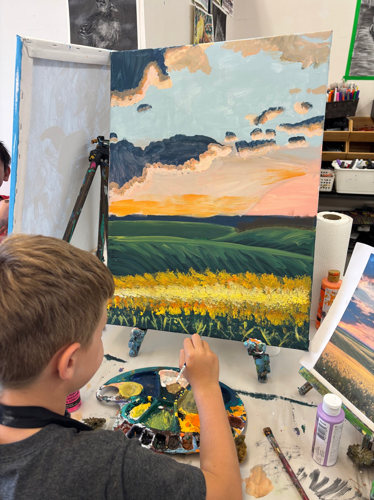 Young boy painting a canola field at Grasby Art Studio