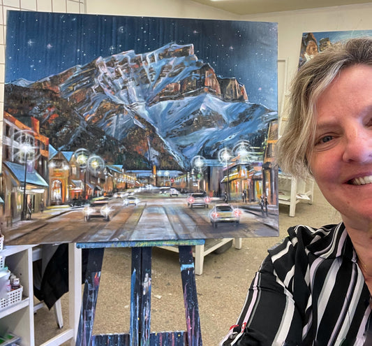 Teresa Grasby in the studio beside a large night painting of Banff Avenue below Cascade Mountain, Grasby Art Studio, NW Calgary