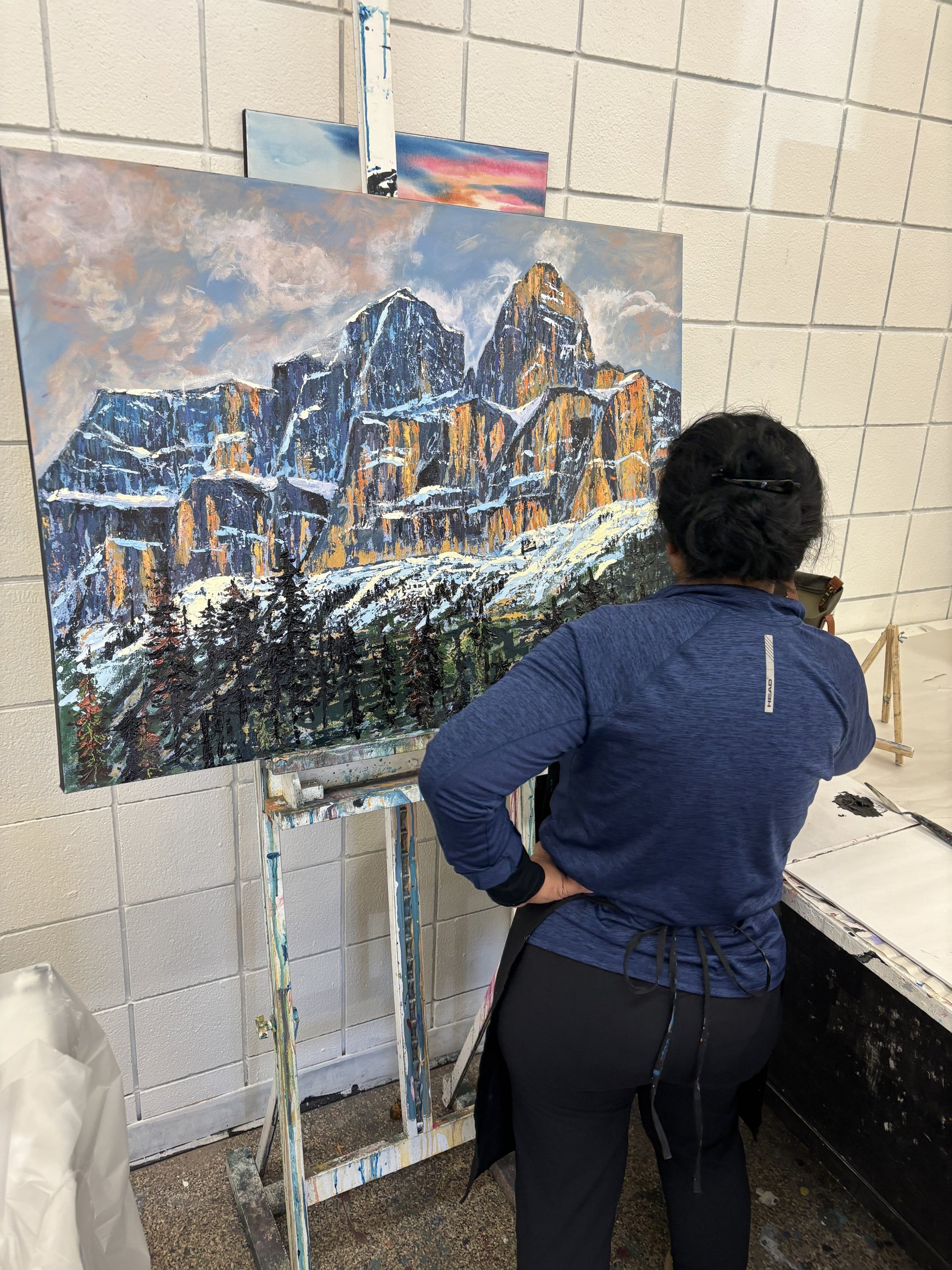 Student at the easel finishing a large Castle Mountain palette knife painting in the Mountain workshop, Grasby Art Studio, NW Calgary